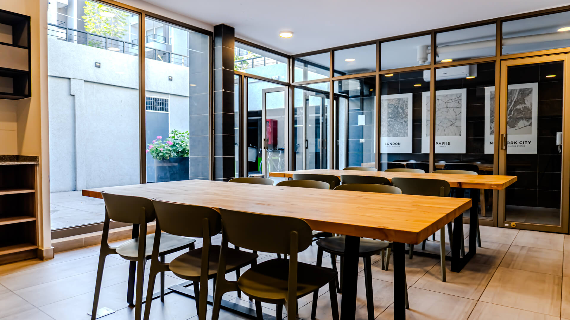 Espacio de cowork con mesas largas de madera y ventanales al patio