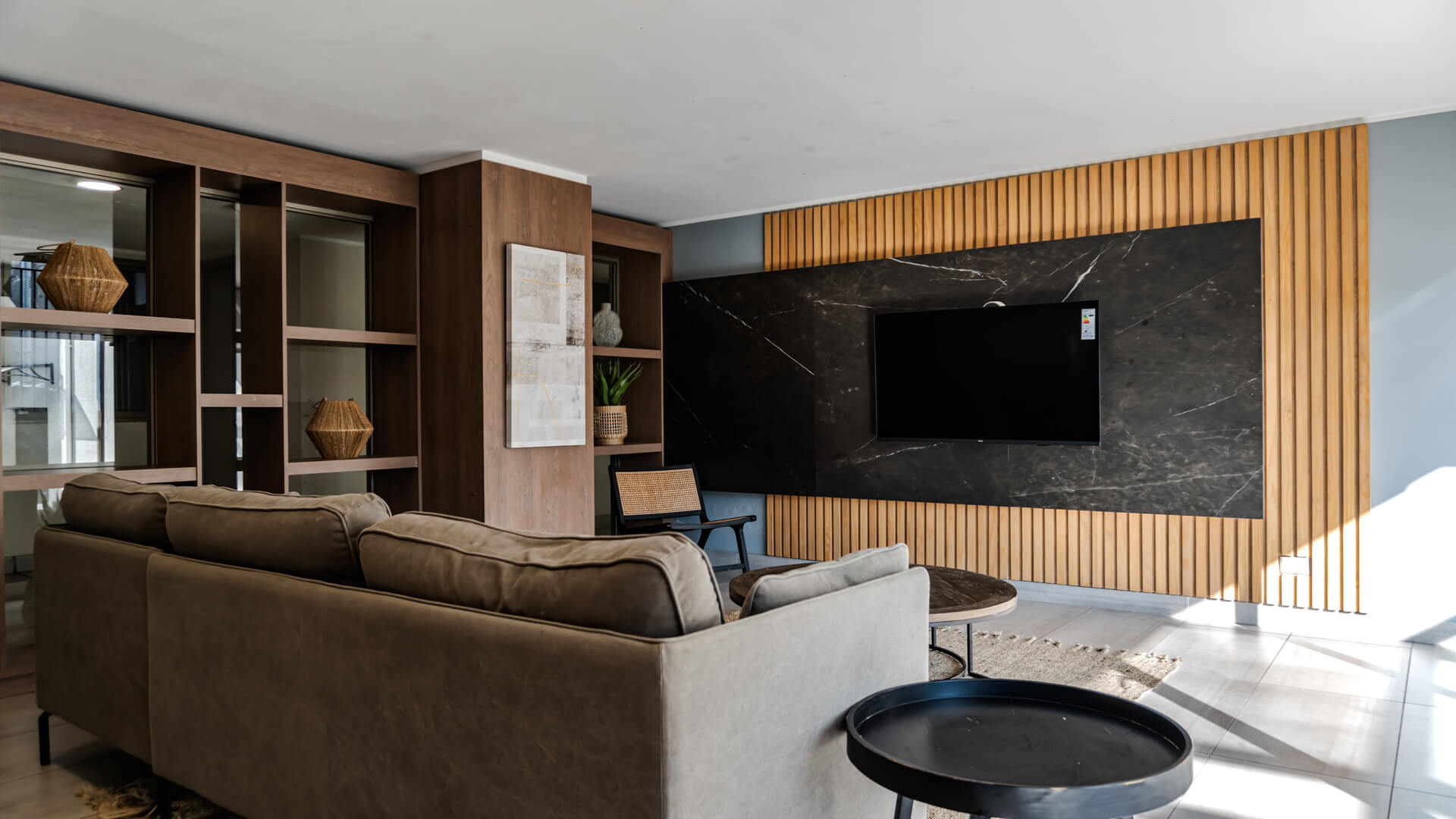 Living común con sofás, televisor y revestimiento de madera